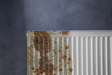 Modern panel radiator affected by rust on grey background