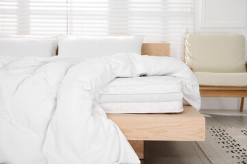 Fototapeta na wymiar Wooden bed with soft white mattress, blanket and pillows indoors