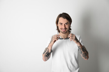 Young man with tattoos on arms against white background