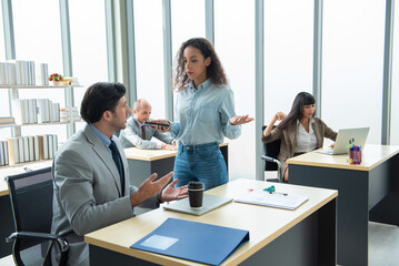 A man and a woman are sitting and discuss at a table chatting to a work colleague.