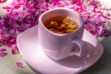 Tea from rose petals. In pink cup, on pink background of rose petals. Flower tea from rose petals