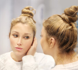 Fototapeta premium woman looking in the mirror in the bathroom and taking care of her skin.Applying the cream..Magic anti-aging cream.