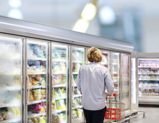  Man choosing frozen food from a supermarket freezer., reading product information