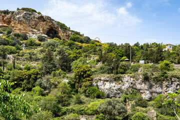 Beautiful mountain, cliff, limestone rock covered with forest. Mediterranean landscape. A cave inside the mountain at the top. Greece, Rethymnon area.