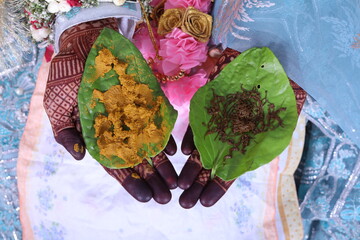indian bride having turmeric and henna on betal leaf on a mehndi laden hand