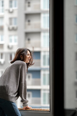 the girl looks at the city from the balcony of the apartment