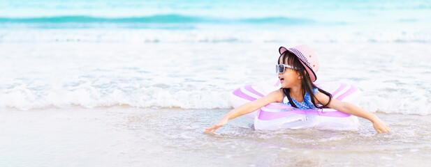 Banner of adorable asian little girl wear sunglass and hat is happy to play sea water on the beach...
