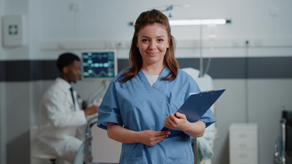 Portrait of woman nurse with medical files to give support to medic in hospital ward. Close up of medical assistant looking at camera ready to help with patient and checkup documents. - Powered by Adobe