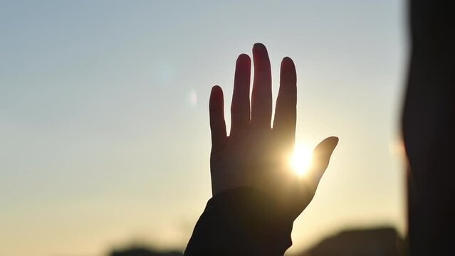 Female hand touching the sun and sunlight passing through fingers