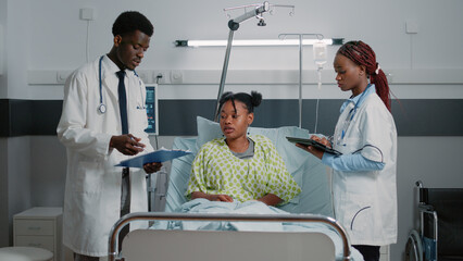 Team of doctors giving assistance to sick woman in bed. Medical physicians doing healthcare checkup...