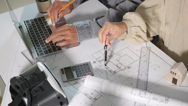 Architect team meeting consult and work for architectural construction project with laptop computer they editing on blueprint paper plans, Architect and engineer design layout together help each other