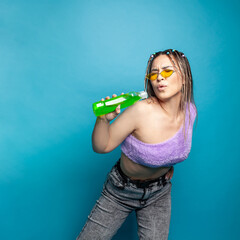 Funny woman singing holding plastic bottle against blue studio wall background