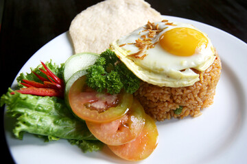 Complete fried rice dish, authentic Indonesian. fried egg topping. chopped fresh tomatoes, lettuce, cucumber and prawn crackers.