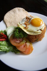Complete fried rice dish, authentic Indonesian. fried egg topping. chopped fresh tomatoes, lettuce, cucumber and prawn crackers.