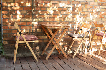 Empty street coffee shop with wooden terrace and brick wall. Wooden chairs and table table in...
