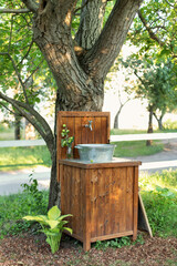 Handmade wooden Wash basin with soap in garden for hands cleaning in summer. Hand outdoor washing facilities to prevent the spread of virus or disease. Vintage outdoor sink for rustic decor in yard	