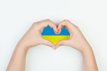 Fototapeta premium Heart with flag of Ukraine in female hands on white background