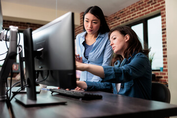 Professional office workers pointing out wrong blueprint of project while using work computer....