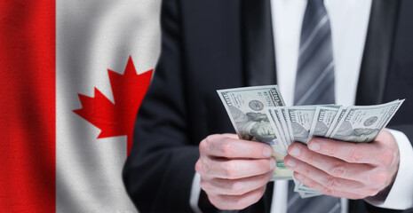Hands holding dollar money on flag of Canada