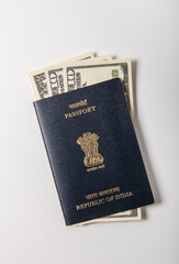 US Dollar currency notes placed inside Indian Passport booklet in white background. Conceptual photo to connote Indian travels to USA or earn dollars.