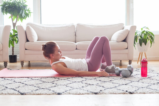 Slim sporty woman doing v-ups abs workout at home