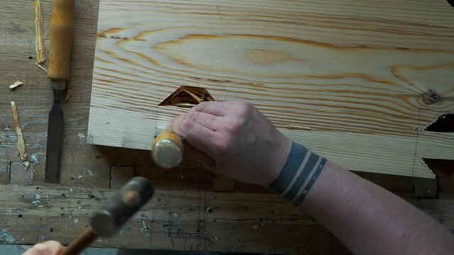 woodworker carving a dovetail eyelet with a chisel