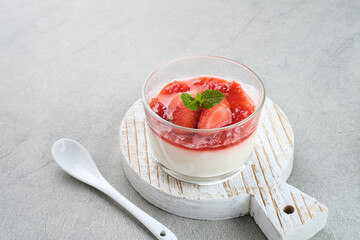 Sweet vanilla silky pudding dessert with strawberry sauce, sliced ​​fresh strawberries and mint on a glass
