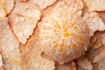 Close-up shot of peeled out tangerine with many peels around. Tasty juicy tangerine on a table