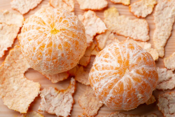 Two peeled off tangerine on wooden table. Close-up shot of tangerines with peel around, eating juicy tangerines