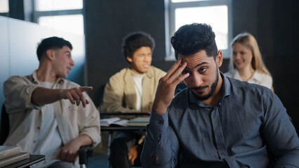 Young excited arab guy student sitting in classroom cannot concentrate on lesson being ridiculed by...