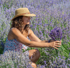 Woman in straw hat with lavender bouquet in the lavender field.