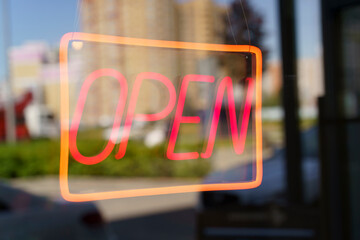 Neon sign open on the glass door of a shop or cafe. Selected focus