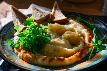 Mashed potatoes in a beautiful serving with paprika, slices of dark bread in triangles, with a slide of microgreens, vegetables spread in a circle, appetizing simple food interesting
