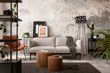 The stylish compostion at concrete living room interior with design gray sofa, wooden coffee table, desk and elegant personal accessories. Loft and industrial interior. Home decor. Template. .