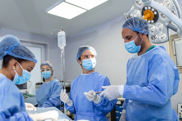 Surgical team performing surgery in modern operation theater,Team of doctors concentrating on a patient during a surgery,Team of doctors working together during a surgery in operating room,