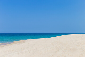 Fototapeta na wymiar Fine sandy beach with clear blue sky background, tropical island beach in south of Thailand, tropical environment