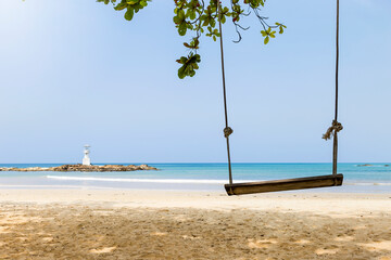 Wooden swing on the beach with lighthouse view, relaxing by the sea, tropical climate
