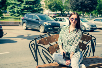 Obraz premium Portrait of a smiling pretty young business woman in glasses walking in the city. Enjoys the sun.