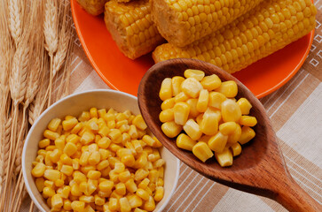 bowl of fresh sweet corn spoon and ears of wheat and corn background