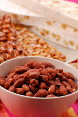 Caramelized sweet nuts bowl and nougats background.