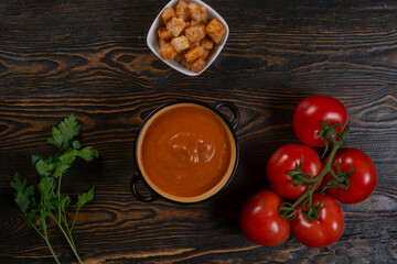 Tomato soup on wooden table, top view