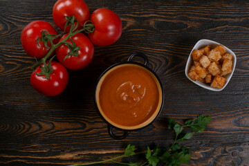 Tomato soup on wooden table, top view