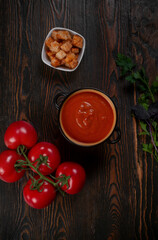 Tomato soup on wooden table, top view