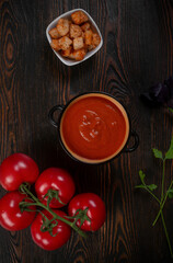 Tomato soup on wooden table, top view