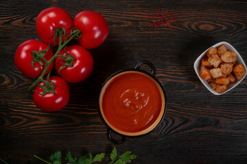 Tomato soup on wooden table, top view