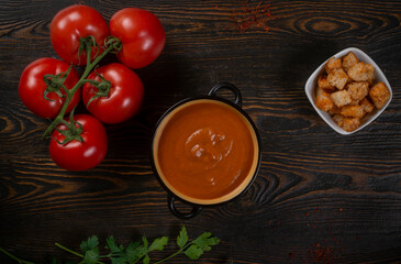 Tomato soup on wooden table, top view