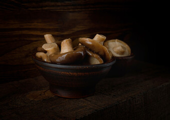 Pickled mushrooms in a clay cup . Rustic food .