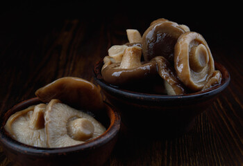 Delicious beautiful pickled mushrooms in a clay cup on a wooden table side view. Salted mushrooms close - up . Rustic food .