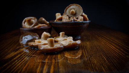 Black milk mushrooms on a wooden table . Beautiful pickled mushrooms .
