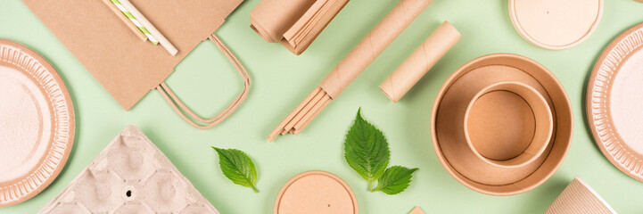 Banner with ecological tableware, paper utensils and wooden bamboo cutlery set over light green...